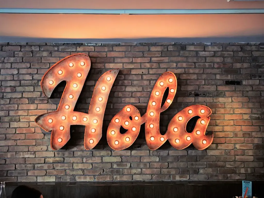 "hola" sign on a brick wall