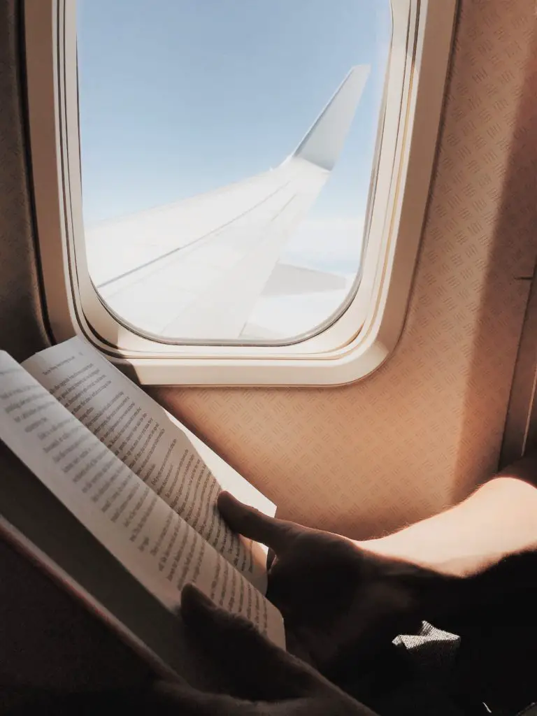 woman reading a book on a plane