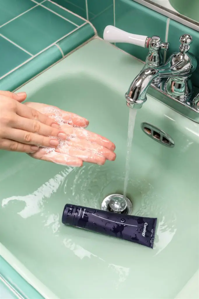 woman washing her face at sink before getting on a long flight